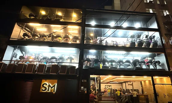 Fachada da SM Fitness Centro iluminada à noite